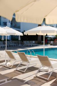 a group of chairs and umbrellas next to a swimming pool at Suites ROC Portonova - Newly Renovated 2026 in Palmanova