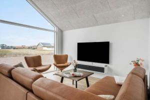 a living room with a couch and chairs and a tv at 394-Harboore-Hermodsvej-8 in Harboør