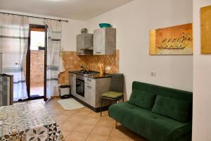 a living room with a green couch and a kitchen at Centro mare residence affitta alloggi in Porto Torres