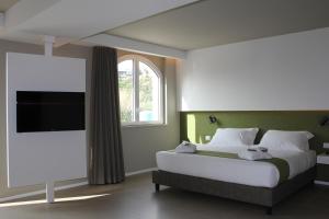 a white bed sitting in a bedroom next to a window at Airone City Hotel in Catania