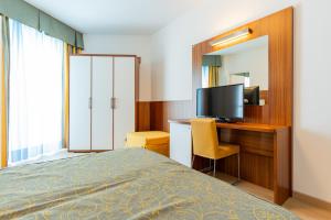 ein Schlafzimmer mit einem Bett und einem Schreibtisch mit Fernseher in der Unterkunft Hotel Touring in Caorle + 60 Fotos