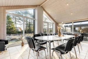 a dining room with a table and chairs and windows at 0259-Romo-Lyngvejen-89-B in Høm