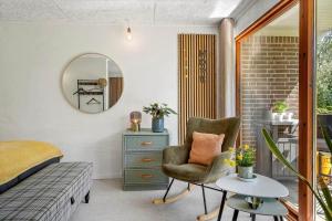 a bedroom with a bed and a chair and a mirror at LF10004-Thyholm-Agertoften-4 in Thyholm