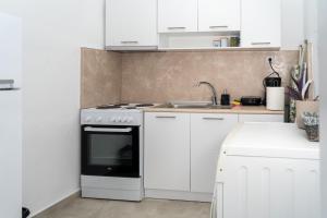 a white kitchen with a stove and a sink at Rodostagma 2 in Rodholívos