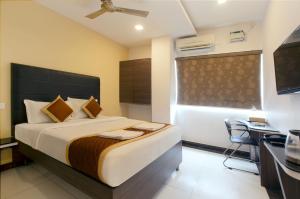 a bedroom with a bed and a desk and a television at Manjhi Stay in Tiruchirappalli +22 photos