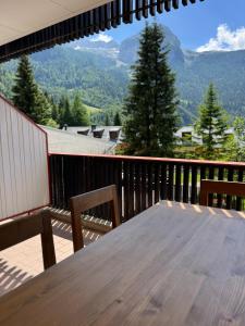 a wooden table on a balcony with a view of mountains at Tra Neve e Lago Mountain Apartment in Sella Nevea
