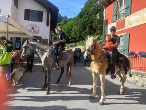 two police officers on horses with a child on a street at Campeggio il Bosco in Entracque