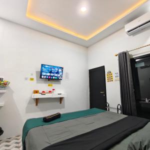 a bedroom with a bed and a tv on the wall at Wisma 11 Oktober in Palangkaraya +2 photos