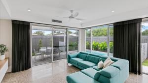 a living room with a blue couch and windows at Luxury Townhouse Maroochydore in Maroochydore