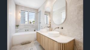 a bathroom with two sinks and a tub and a mirror at Luxury Townhouse Maroochydore in Maroochydore