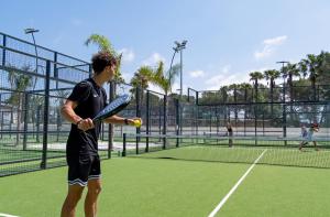 a man holding a tennis ball and racket on a tennis court at Residence La Palmeraie in Fréjus