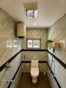 a bathroom with a white toilet and a window at Pinto Eden Home Stay 5 Star Luxury Stay in Chikmagalur in Sangameswarpet +57 photos