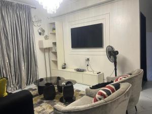 a living room with two chairs and a tv on a wall at Ivaeli Apartment in Lagos