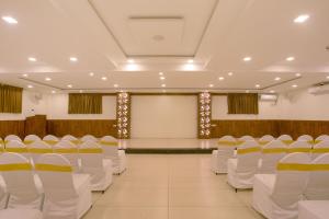 a banquet hall with white chairs and a stage at Manjhi Stay in Tiruchirappalli
