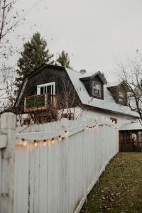 a white fence in front of a house at Domaine Taïga - Parc animalier en forêt in Sainte-Agathe-des-Monts