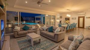 a living room with couches and a pool at Maltese Luxury Villas - Sunset Infinity Pools, Indoor Heated Pools and More! in Mellieħa +275 photos