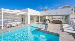 a villa with a swimming pool and a dining room at Maltese Luxury Villas - Sunset Infinity Pools, Indoor Heated Pools and More! in Mellieħa