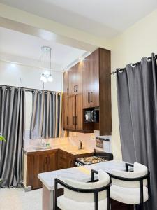 a kitchen with wooden cabinets and a table and chairs at Modern 1BR Apartment with Pool & Sauna Kampala in Kira