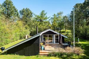 a black cabin with a deck in the grass at LF16082-Farso-Kjeldhoj-82 in Ertebølle