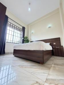 a bedroom with a large bed and a large window at Modern 1BR Apartment with Pool & Sauna Kampala in Kira +8 photos