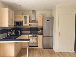 a kitchen with wooden cabinets and a stainless steel refrigerator at Chambre proche du Polygone scientifique - EdF - Schneider - GEM in Saint-Martin-le-Vinoux