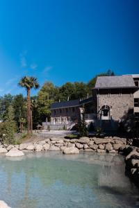 a house next to a river with rocks in front at Domaine de Beaucens in Beaucens
