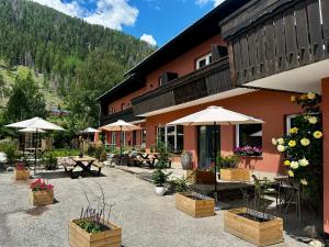 a building with tables and umbrellas in a courtyard at Berghaus Wanderlust in Mallnitz