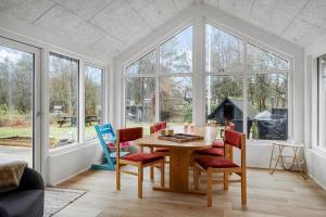 a dining room with a table and chairs and windows at LF18116-Veslos-Agerovej-6 in Amtoft +21 photos