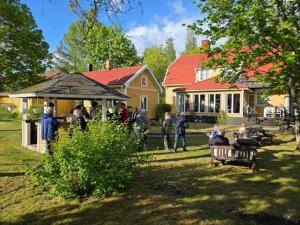 a group of people sitting on a bench in front of a house at Hotell Tussilago i Essunga in Nossebro