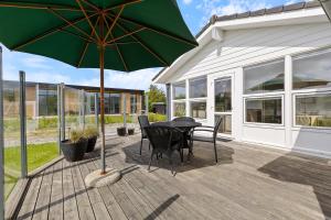 a patio with a table and a green umbrella at Feriehus 1120 in Ringkøbing