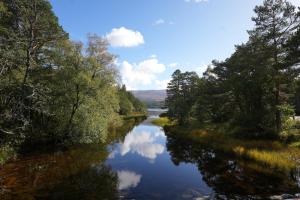 a river with trees and reflections in the water at Cruachan B & B in Tomintoul