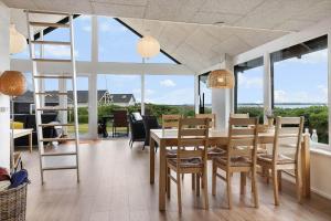 a dining room with a table and chairs and windows at LF12715-Vinderup-Vibevej-15 in Ejsingholm