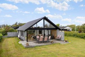 a house with glass doors and chairs in a yard at LF12715-Vinderup-Vibevej-15 in Ejsingholm