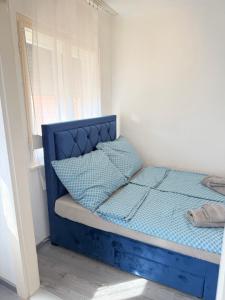 a blue bed in a room with a window at Beni Apartman in Szeged