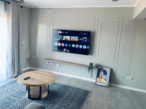 a living room with a table and a flat screen tv at The Penguin Nest in Gaborone