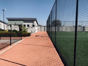 a fence with two tennis courts on a tennis court at The Penguin Nest in Gaborone