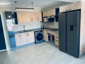 a kitchen with a refrigerator and a washing machine at The Penguin Nest in Gaborone