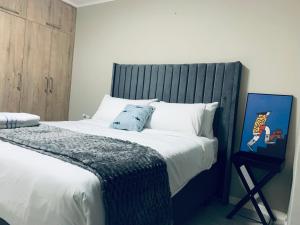 a bedroom with a large bed with a blue headboard at The Penguin Nest in Gaborone +8 photos