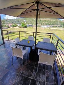 a table and chairs on a balcony with an umbrella at Jate Guest House in Maseru