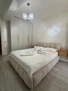 a bedroom with a large white bed with a chandelier at ND Central Apartment in Râmnicu Vâlcea