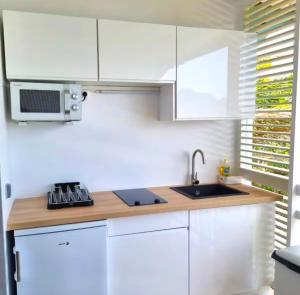 a kitchen with white cabinets and a sink at Studio Calm Blue in Le Diamant