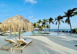 a beach with two lounge chairs and a straw umbrella at Studio Calm Blue in Le Diamant