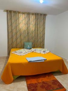 a bed with an orange comforter in a room at Vacances El Haouaria in El Haouaria