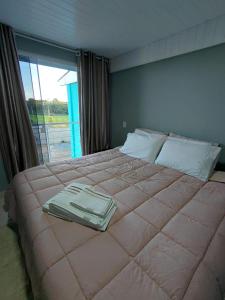 a large bed in a bedroom with a large window at Pousada Por do Sol in Lapa