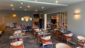 a man standing in a restaurant with tables and chairs at Pandora Hotel in St. Peter Port