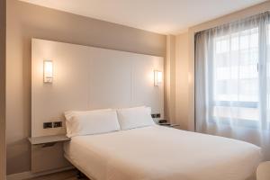a bedroom with a large white bed and a window at B&B HOTEL Castellón in Castellón de la Plana