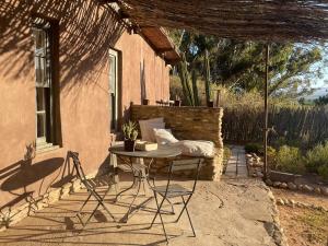 a patio with a table and chairs in front of a house at Strooi Kooi - Unique Strawbale Cottage in Calitzdorp