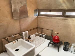 a bathroom with a sink and a red appliance at Strooi Kooi - Unique Strawbale Cottage in Calitzdorp