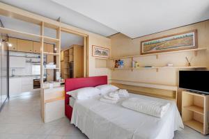 a bedroom with a red bed and a kitchen at Appartamento Vista Lago Ghiffa in Ghiffa