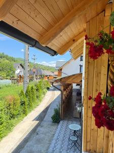 a wooden building with a patio with red flowers at Domeniul Ursului in Valea Stejarului